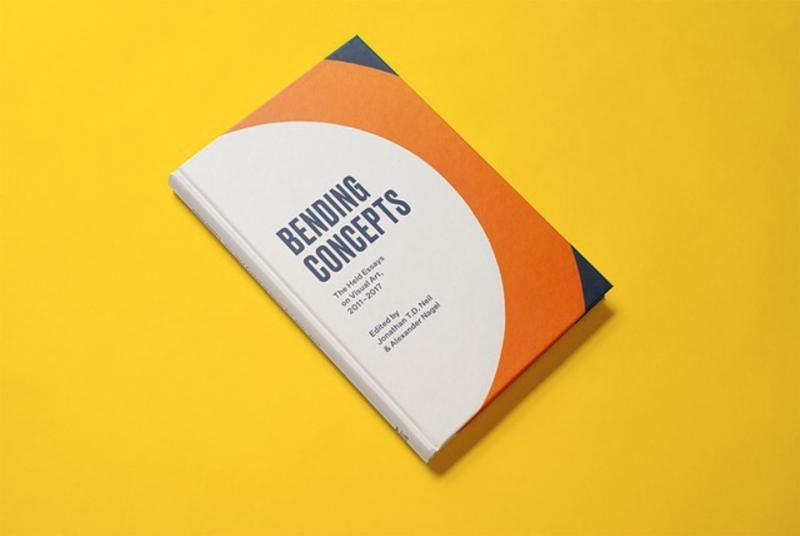 Hardcopy book titled Bending Concepts, with a white, orange, and navy cover, resting on a bright yellow backdrop.
